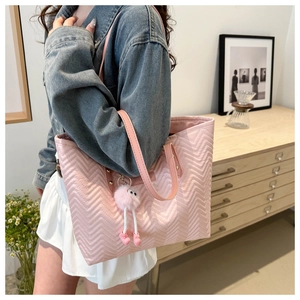 Detailed view of pink quilted tote bag with cute plush monster pendant in daily use