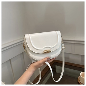 Detail of white semi-circular saddle bag with golden metal buckle and sleek matte finish