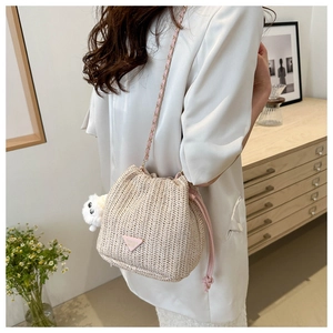 Detail of straw bucket bag with pink drawstring and cute plush chicken charm