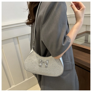 Close-up of silver rhinestone underarm bag with a metallic bow and sleek shoulder strap