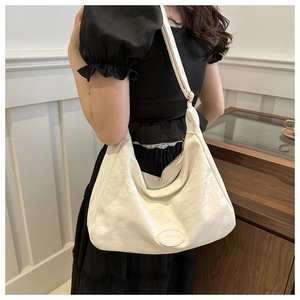 Détail d'un sac cabas plissé blanc montrant la texture douce et la bandoulière élégante