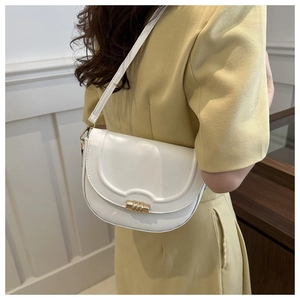 Detail of white saddle bag with scalloped edge design and golden metal buckle