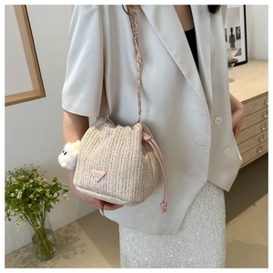 Detail der gewebten Strohbeuteltasche mit rosa Kordelzug, Kette und niedlichem Hasenanhänger