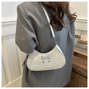 Close-up of sparkling silver rhinestone underarm bag featuring a metallic bow detail