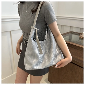 Détail du sac cabas argenté métallisé avec étiquette mode et bandoulière en cuir gris