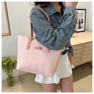 Detail of pink quilted shoulder tote bag with V-shaped texture and metal logo plate