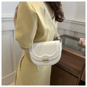 White semi-circular saddle bag with gold metal lock worn over a yellow dress