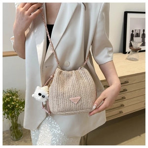 Detail der Stroh-Eimertasche mit rosa Kettengurt und weißem Pompon am Modell