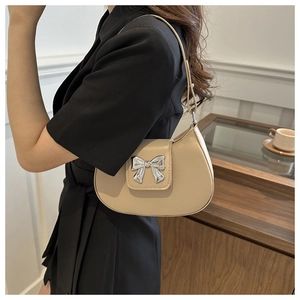 Detail of apricot crescent bag featuring a metallic silver bow on smooth faux leather