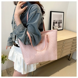 Detail of pink quilted tote bag with wave stitching and leather handle with metal rivets
