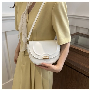 Detailaufnahme der weißen Satteltasche mit goldenem Metallschloss und verstellbarem Gurt
