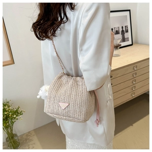 Detail of straw bucket bag with V-shaped weave, pink drawstring and gold chain strap