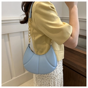 Close-up of light blue quilted leather underarm bag with gold chain strap detail