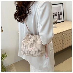 Detail of woven straw bucket bag with pink shoulder strap and drawstring closure
