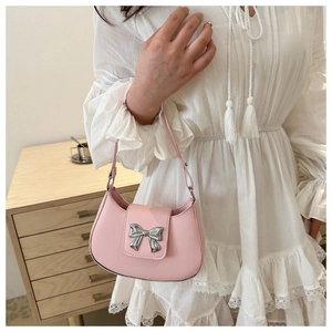 Detailed side view of pink crescent shoulder bag with silver bow on a lace dress