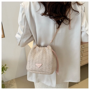 Close-up of woven straw bucket bag with pink triangular patch and gold chain strap