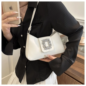 Close-up of white leather underarm bag featuring a luxury sparkling rhinestone buckle