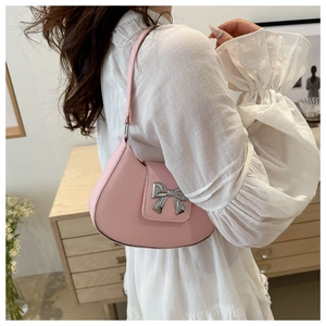 Detailed side view of a pink bow shoulder bag worn over a white ruffled blouse