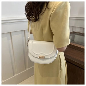 Close-up of white leather saddle bag featuring a stylish gold cylindrical metal buckle