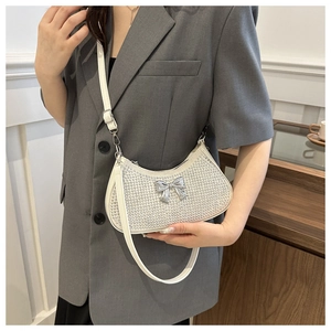 Detail of white rhinestone baguette bag with silver bow and leather strap