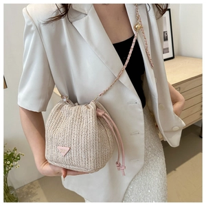 Close-up of straw bucket bag featuring pink leather drawstring and chain strap detail