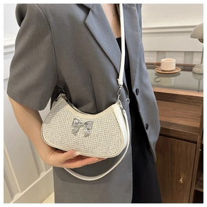 Detail of white crescent rhinestone shoulder bag with silver bow accent on model