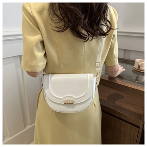 Detail of white saddle bag with distinctive cylindrical gold buckle and smooth leather finish