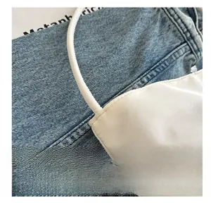 Close-up of fine stitching on the white satin strap of a minimalist underarm bag