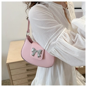Pink crescent underarm bag with silver metal bow detail and zipper closure shown on shoulder