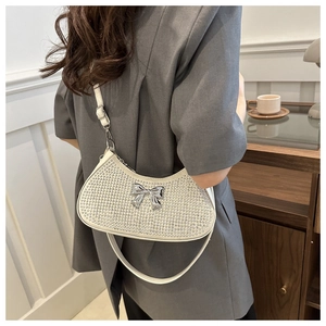 Close-up of rhinestone shoulder bag with silver bow detail on a model in a cafe