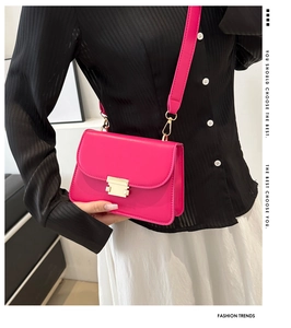 Detail showing the golden rectangular lock on a magenta small square crossbody bag