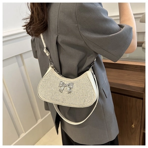 Close-up of white rhinestone half-moon shoulder bag with metal bow detail