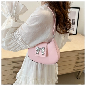 Detail of pink PU underarm bag with a silver metal bow and elegant semicircular silhouette