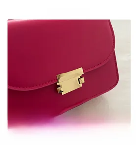 Close-up of fuchsia leather bag with refined gold metal clasp and pyramid stud details