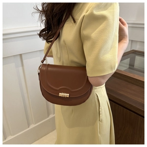 Brown matte leather saddle bag with cylindrical metal buckle and embossed lid detail