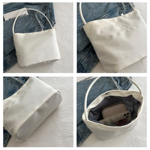 Detail view of white nylon shoulder bag with onwards and upwards embroidery and interior space