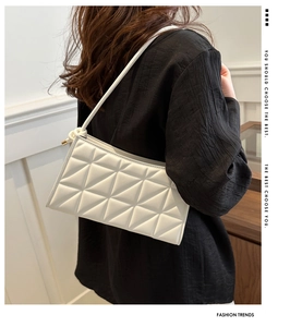 Detail of white quilted crossbody bag with geometric patterns and knotted shoulder strap