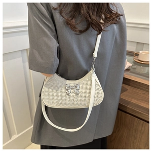 Close-up of white rhinestone handbag with silver metal bow and shoulder strap detail