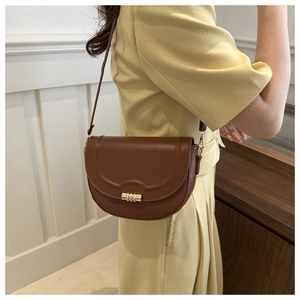 Detailed side view of brown PU saddle bag with gold metal clasp on a model's shoulder