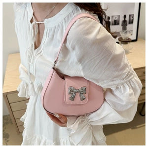 Detailed close-up of a pink crescent-shaped shoulder bag with a metallic silver bow