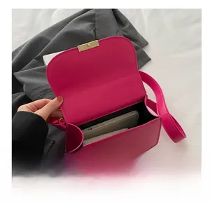 Detail shot showing the interior capacity of a hot pink crossbody bag with a gold lock