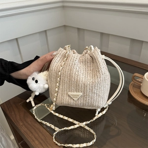 Minimalist cream woven bucket bag with metal chain strap and cute white plush ball charm