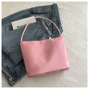 Pink minimalist handbag displayed on textured fabric next to denim jacket and a book