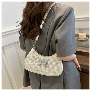 Detail of white rhinestone crescent bag featuring a silver metal bow accent