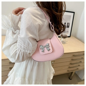 Side view of a soft pink crescent bag with a silver bow on a white ruffled dress