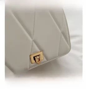 Detailed close-up of white quilted leather texture and elegant gold twist lock closure