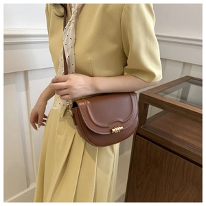 Detail of retro dark brown saddle bag with gold cylinder lock and sleek leather texture