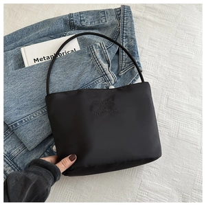 Close-up of black nylon shoulder bag with onwards and upwards text on denim