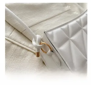 Detailed view of white quilted leather texture with gold ring and knotted strap attachment