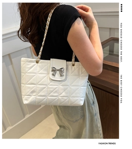 Detail of white quilted leather tote with silver bow buckle and woven metal chain strap